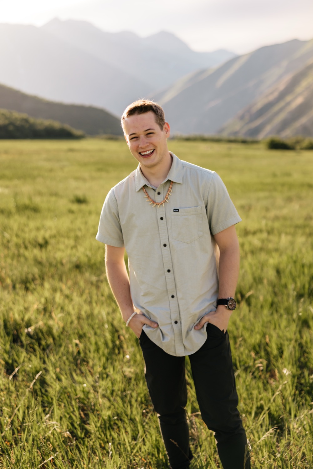 Colby Taylor smiling in a grassy field with mountains behind him